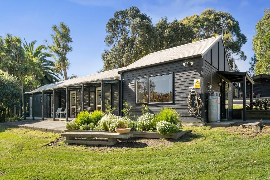 une petite maison noire avec des plantes dans une cour dans l'établissement The Bunkhouse - The Lodge Te Horo, à Te Horo