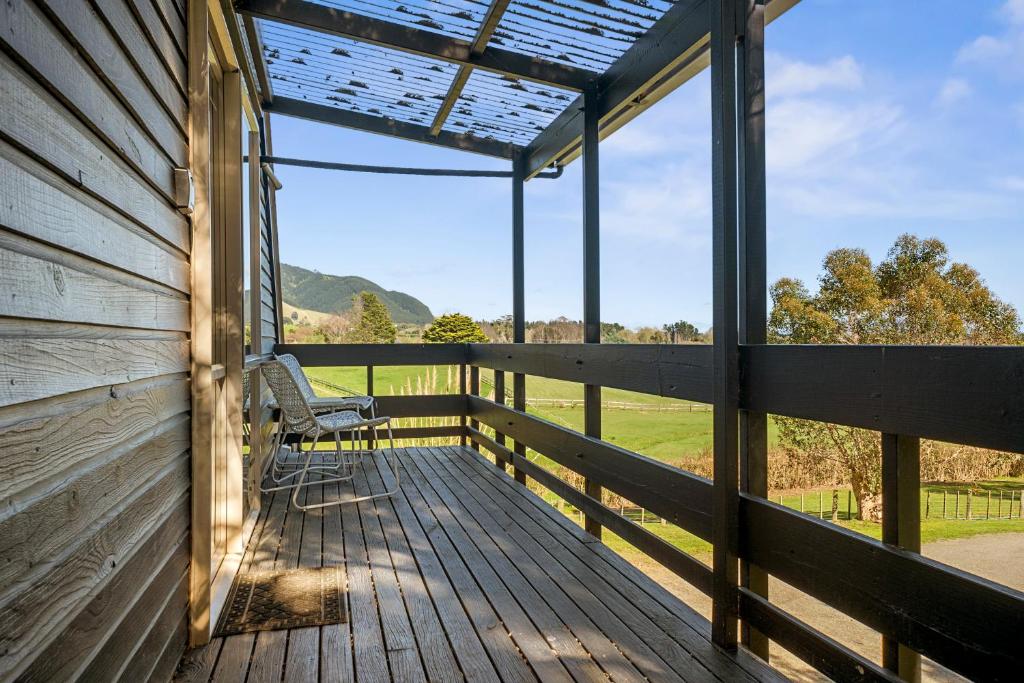 een veranda met een bank en uitzicht op een veld bij The Apartment - The Lodge Te Horo in Te Horo
