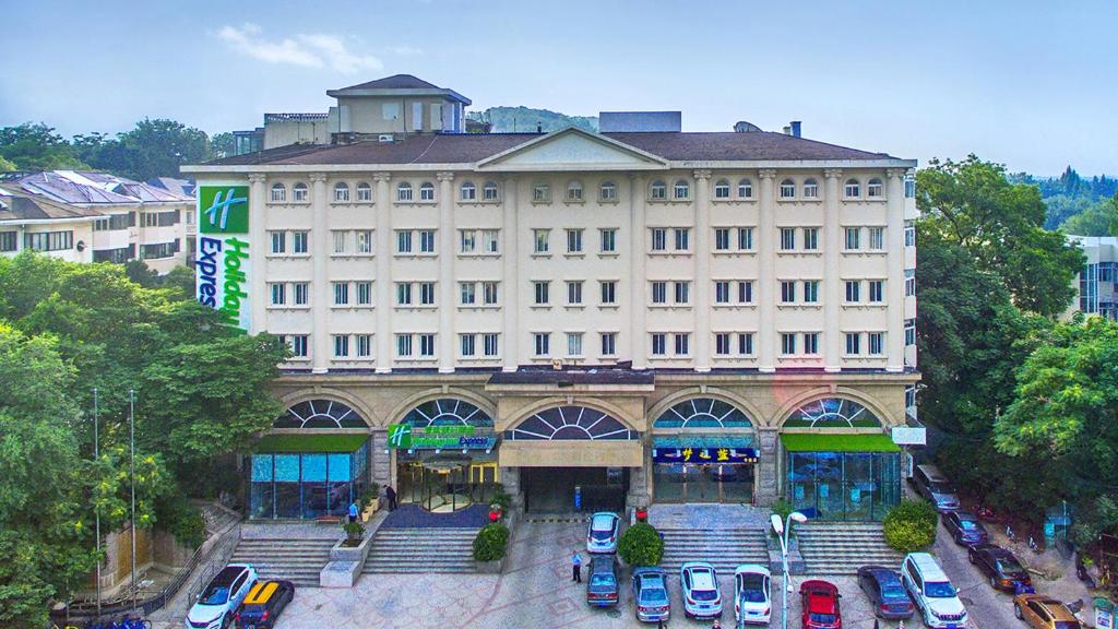 a large building with cars parked in a parking lot at Holiday Inn Express Nanjing Xuanwu Lake, an IHG Hotel in Nanjing