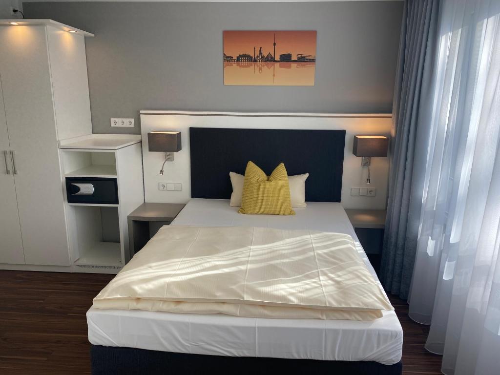 1 dormitorio con 1 cama blanca grande con almohadas amarillas en Mirage City Hotel Stuttgart Zentrum, en Stuttgart