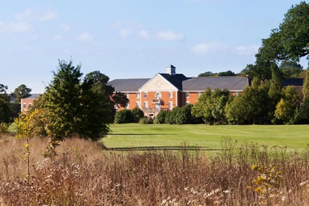 a house in the background with a golf green at Whittlebury Hall and Spa in Whittlebury