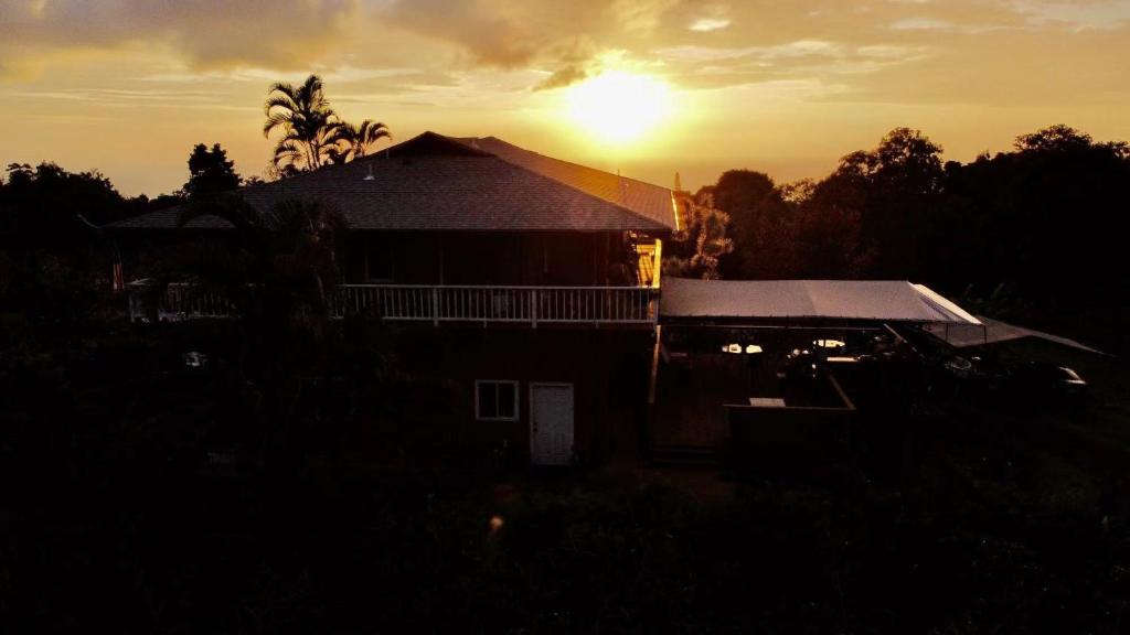 a house with the sun setting in the background at Coffee Garden in Captain Cook