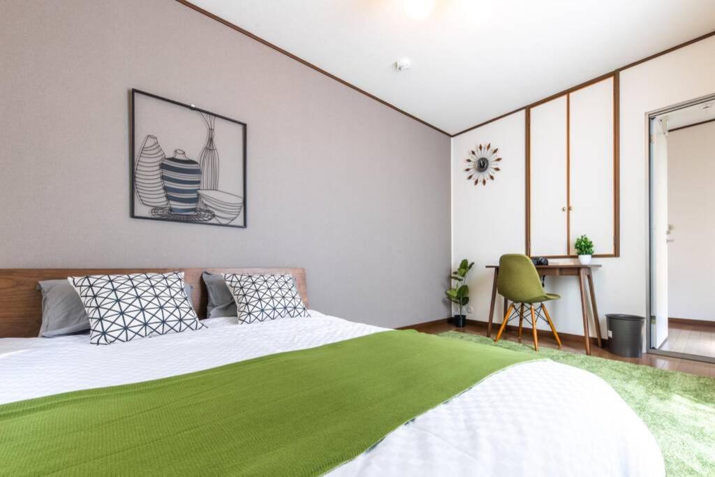 a bedroom with a green bed and a chair at Urban Stay Shinagawa in Tokyo