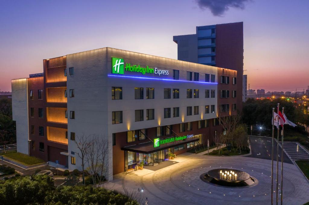 a hotel building with a lit up sign on it at Holiday Inn Express Shanghai Kangqiao, an IHG Hotel in Shanghai