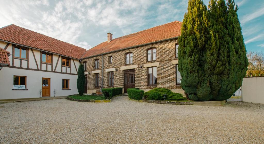 a large brick building with a large tree in front of it at La Chambre D'amis LA COSTIGNIERES in Montgueux