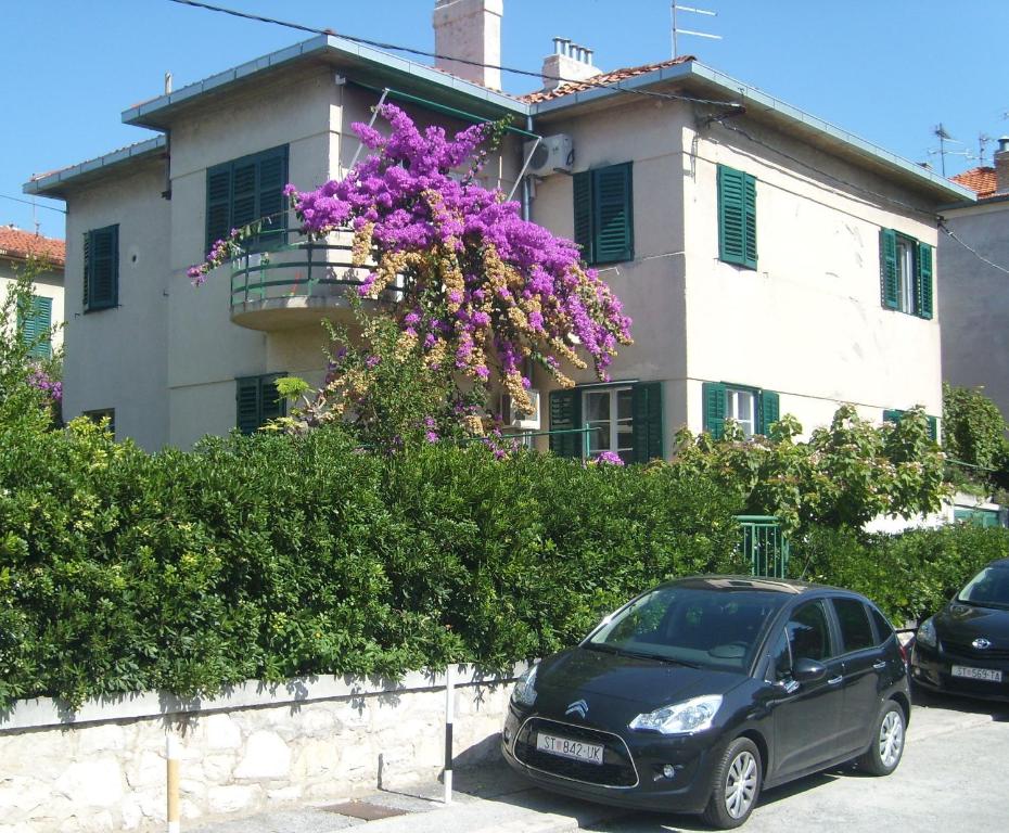 a black car parked in front of a building with purple flowers at Studio Mary in Split