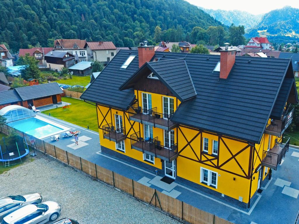 uma casa amarela com um telhado preto e uma piscina em Willa Szczepaniakówka em Szczawnica