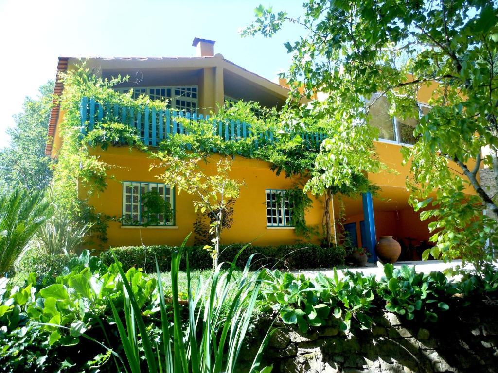 una casa amarilla con muchas plantas en Quinta das Tamengas, en Tentúgal