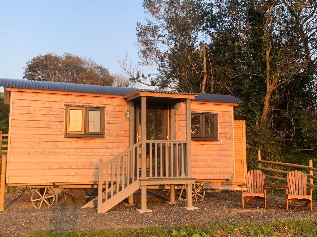 eine Holzhütte mit einer Veranda und 2 Stühlen in der Unterkunft Lle Mary - Beautiful views, Hot tub, Secluded, Dog Welcome, Barmouth in Llanddwywe