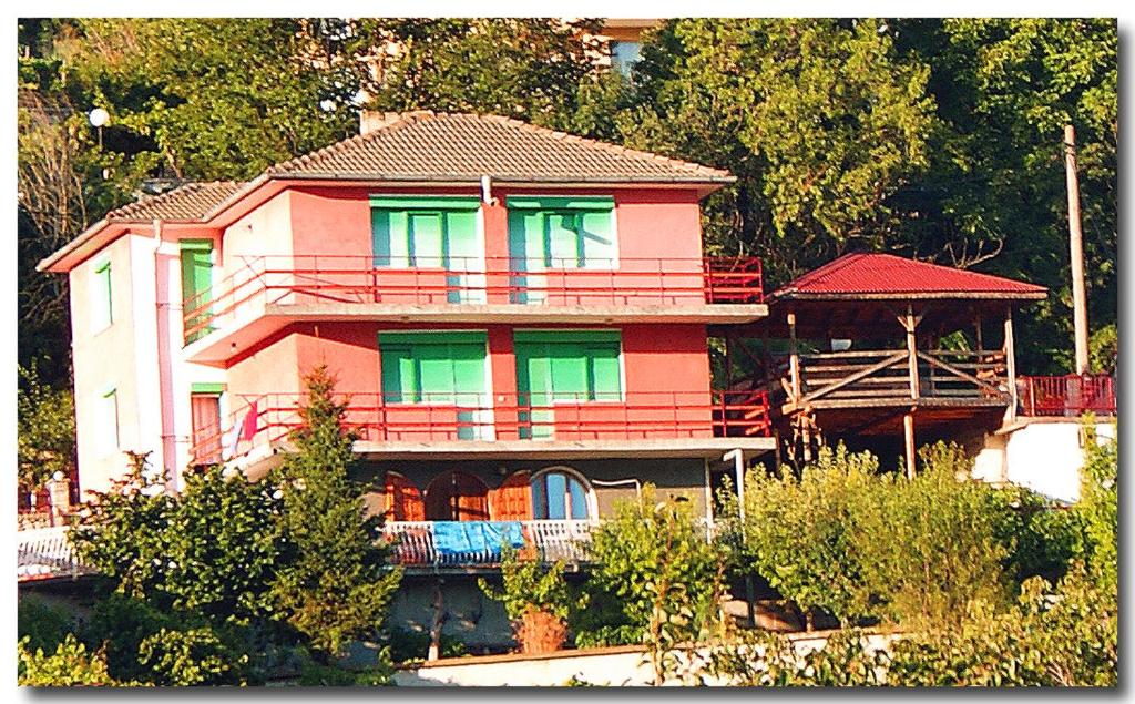 duży różowy dom z zielonymi oknami w obiekcie Vila Dionis w Bałcziku