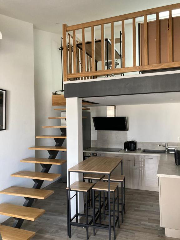 Una escalera que conduce a un loft con mesa en studio meublé du bourg en Puymiclan