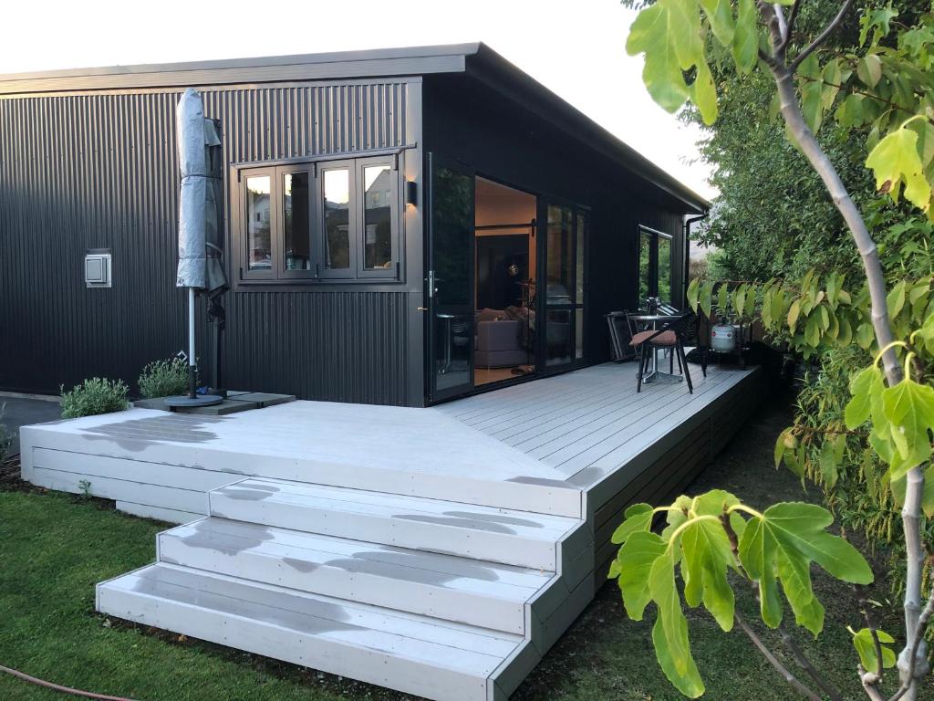 a house with a wooden deck in the yard at Te Toka - Self Contained in Kelvin Heights in Queenstown