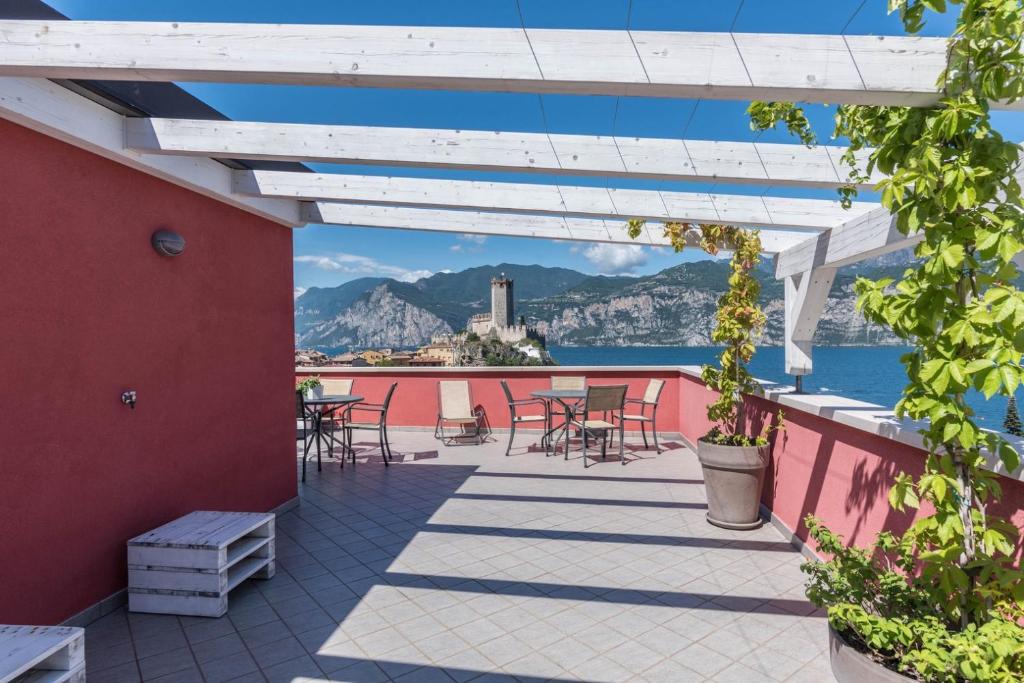 eine Terrasse mit Tischen und Stühlen und Blick auf das Wasser in der Unterkunft APPARTAMENTI Residence La Pergola in Malcesine