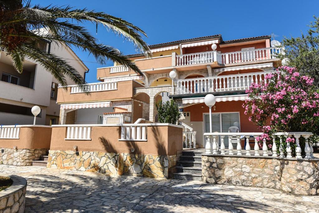 a large building with balconies and a palm tree at Apartments Bella Sky II in Novalja