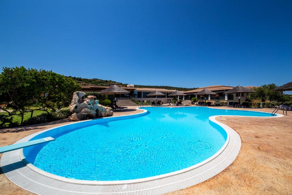 a large blue swimming pool in a yard at Hotel Costa Caddu in San Teodoro