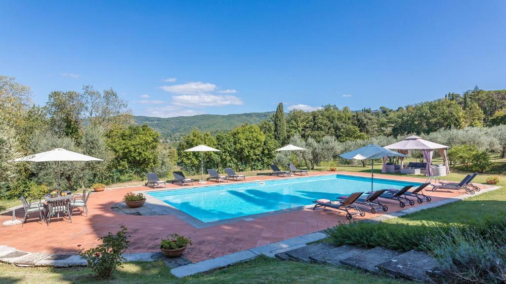 una piscina con muebles de exterior y sombrillas en VILLALTA 18&2, Emma Villas, en Arezzo