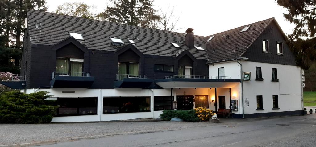 un grand bâtiment blanc avec un toit noir dans l'établissement Hotel Haus Koppelberg, à Wipperfürth