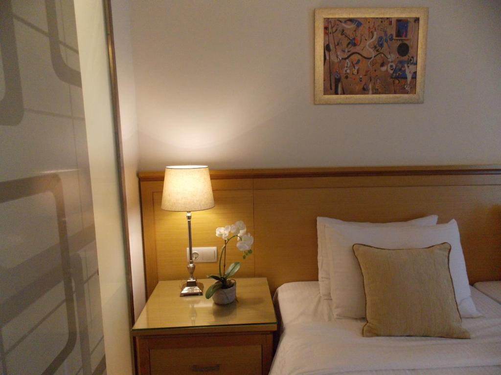 Cette chambre d'hôtel comprend un lit avec une lampe et des fleurs. dans l'établissement Hotel Alexandros, à Anchialos