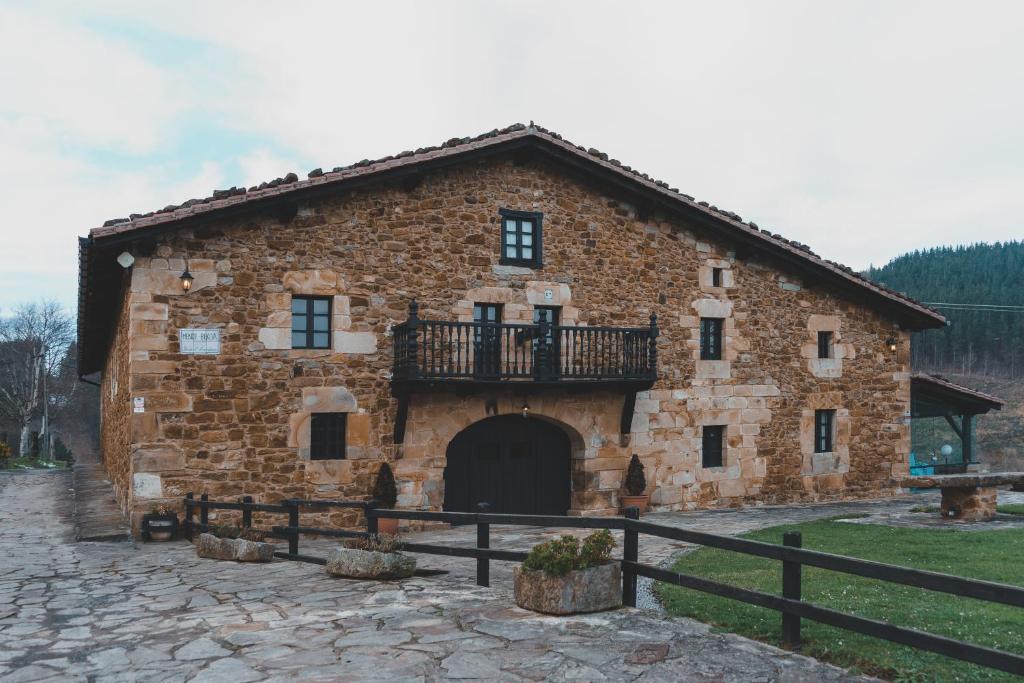 um grande edifício de pedra com uma varanda em MendiGoikoa Bekoa em Axpe