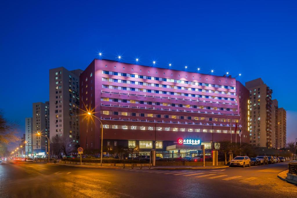 een groot roze gebouw met 's nachts verlichting bij Beijing Commercial Business Hotel in Beijing