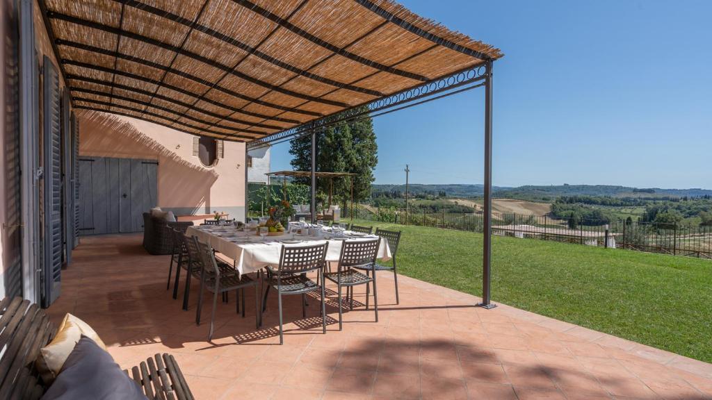 eine Terrasse mit einem Tisch und Stühlen unter einer Pergola in der Unterkunft Villa Il Pino 12, Emma Villas in Certaldo