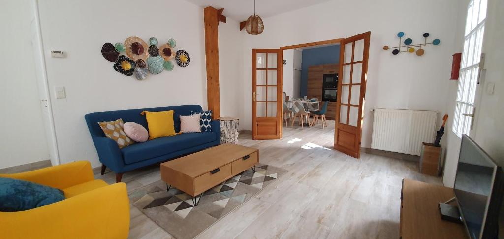 uma sala de estar com um sofá azul e uma mesa em Maison de ville, Bergerac historique tout à pied em Bergerac