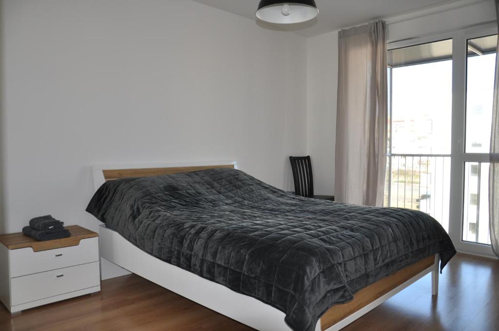 ein Schlafzimmer mit einem Bett und einem großen Fenster in der Unterkunft WROCLOVE_NET APARTMENTS in Breslau