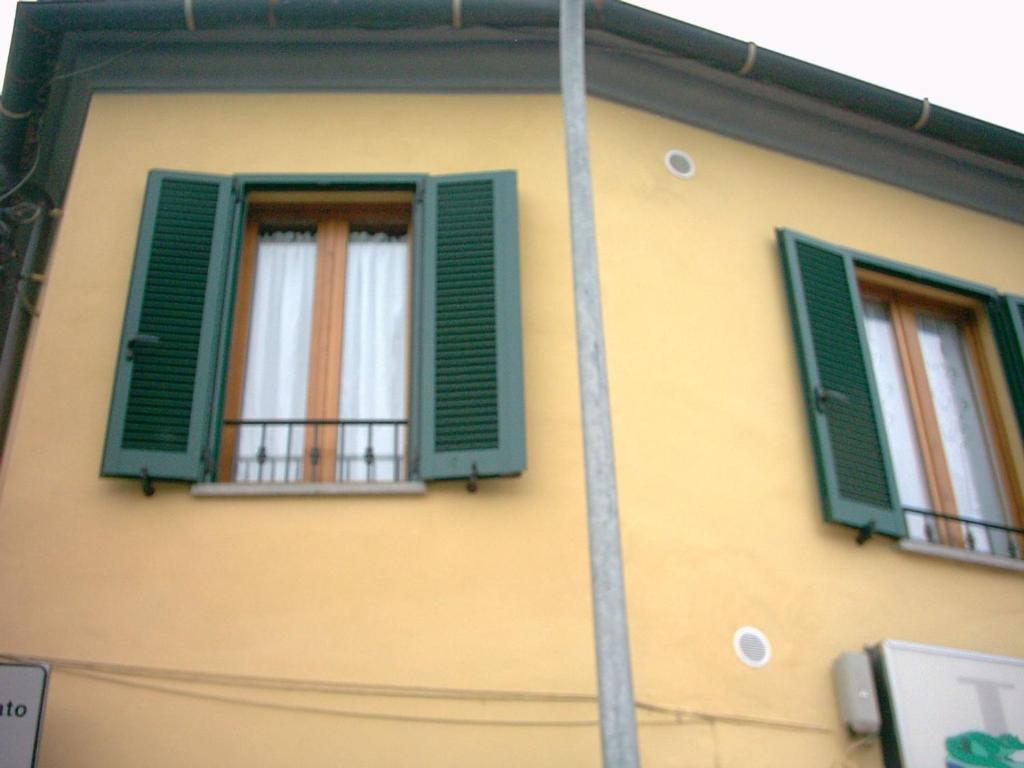 a yellow building with green shutters and a balcony at Appartamenti LEVANTE e LIBECCIO in Follonica
