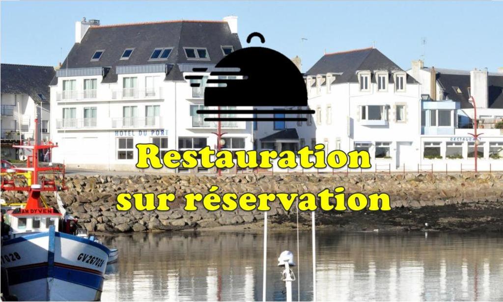 Plobannalec-LesconilにあるLogis Hotel Du Portの一部の建物の隣の水上に座る船