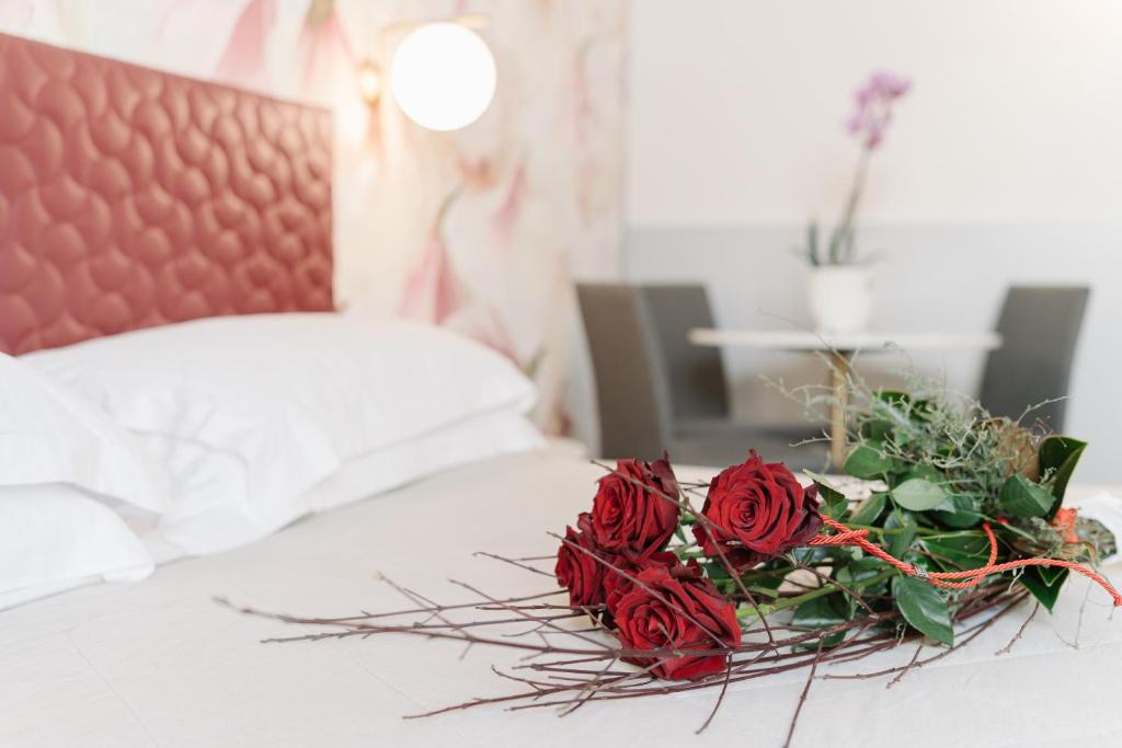 ein Strauß roter Rosen auf einem Bett in der Unterkunft Hotel Giulietta e Romeo ***S in Verona