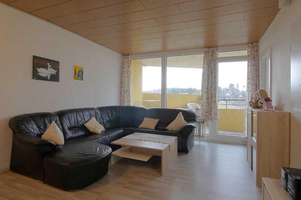 ein Wohnzimmer mit einem schwarzen Ledersofa und einem Tisch in der Unterkunft Apartment 527 in Hohegeiß