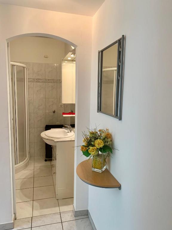 uma casa de banho com um lavatório e um vaso de flores sobre uma mesa em Apartment Locarno-Lido em Locarno