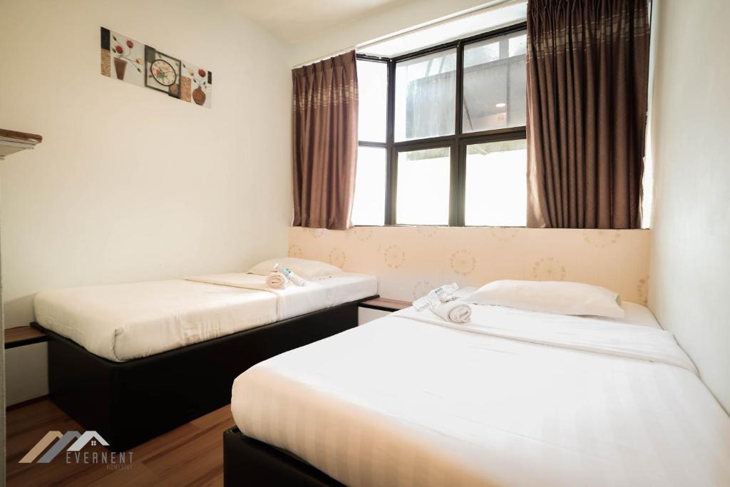 two beds in a small room with a window at Welcome Inn by Evernent @ Pelita Commercial, Miri in Miri