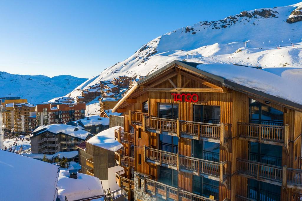a hotel with a snow covered mountain in the background at Langley Hôtel Tango in Val Thorens