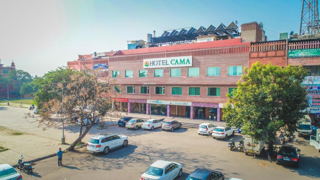 a large building with cars parked in a parking lot at Hotel Cama in Chandīgarh