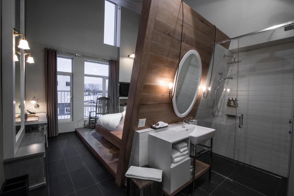 a bathroom with a sink and a shower and a mirror at Hôtel & Spa Le Germain Charlevoix in Baie-Saint-Paul