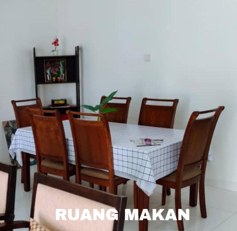 a dining room with a white table and wooden chairs at OneFamily Homestay in Kuala Terengganu