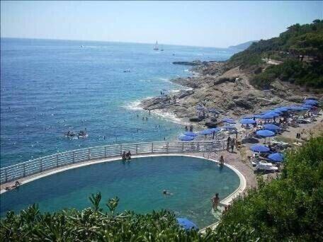 uma piscina numa praia junto ao oceano em Villa Capo D'arco em Porto Azzurro