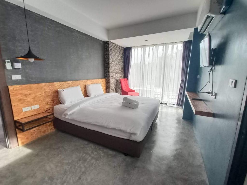 um quarto com uma cama grande e uma cadeira vermelha em Modern Budget Hotel em Hat Yai
