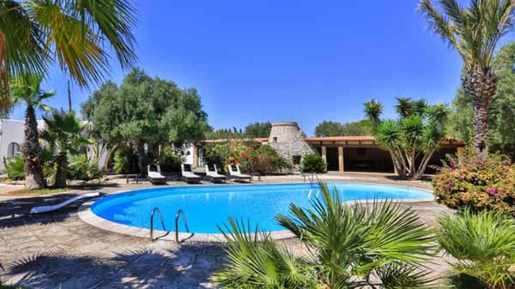 une piscine bordée de palmiers et une maison dans l'établissement Villa Manco 12, Emma Villas, à Gagliano del Capo