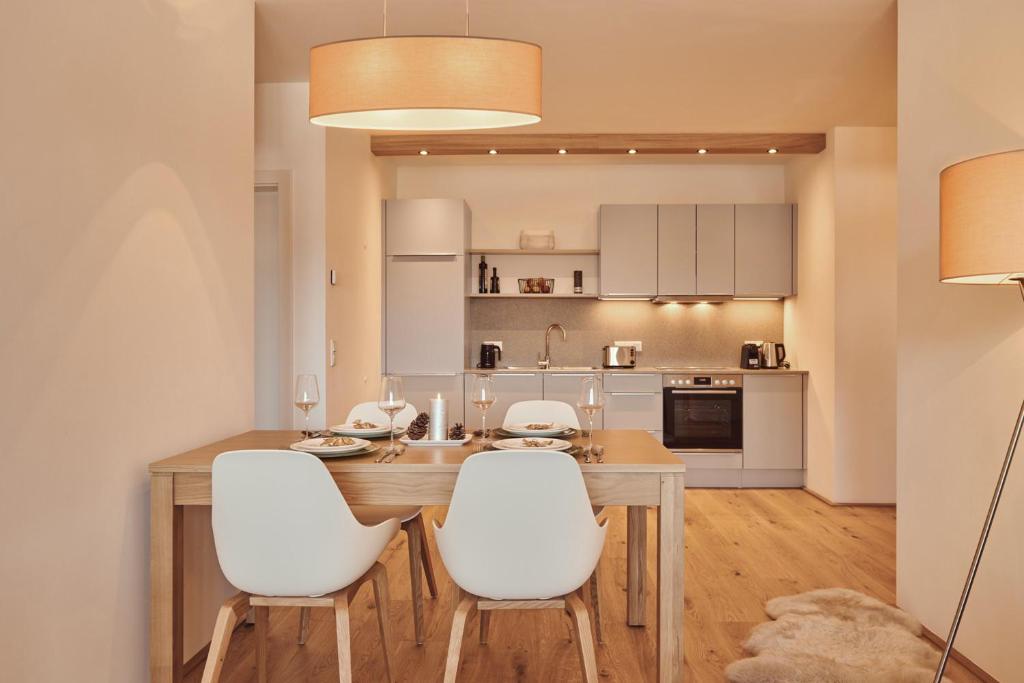 cocina y comedor con mesa de madera y sillas blancas en die Tauplitz Lodges - Wasserfall Lodge C4 by AA Holiday Homes en Tauplitz