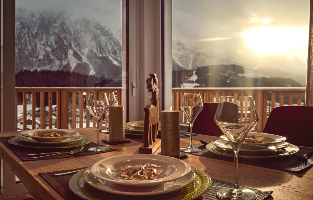 een houten tafel met borden en wijnglazen op een balkon bij die Tauplitz Lodges - Bergblick Lodge B6 by AA Holiday Homes in Tauplitz