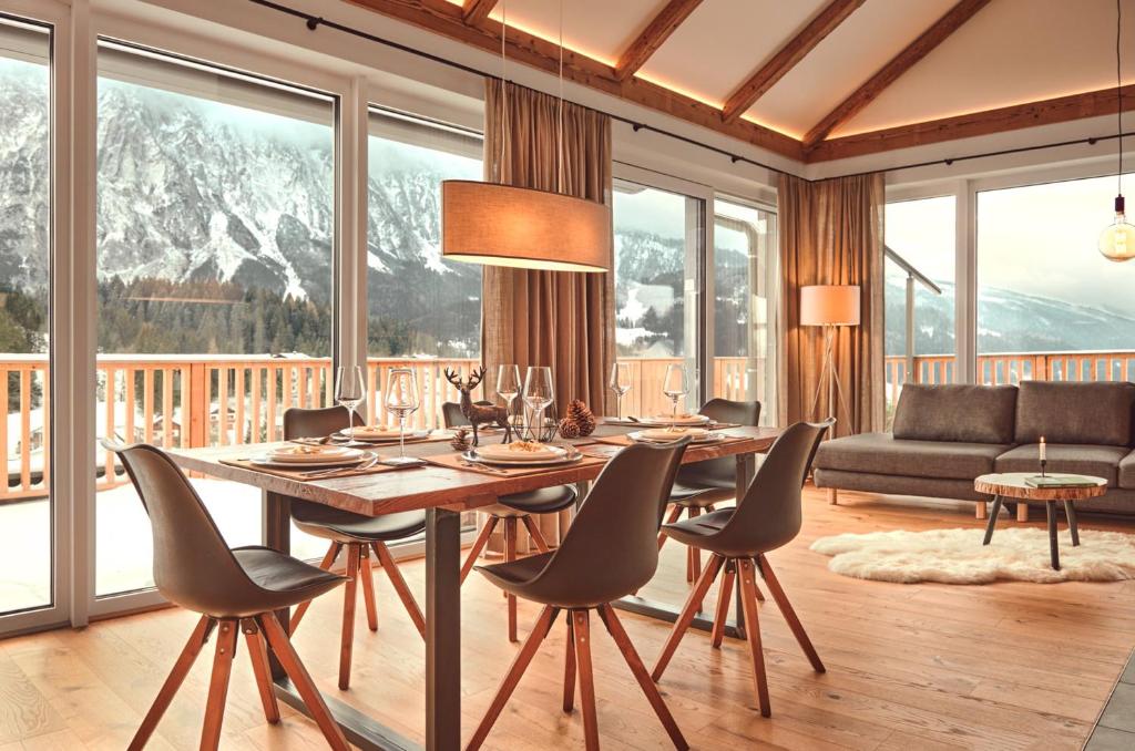 a dining room with a table and chairs and mountains at Die Tauplitz Lodges - Penthouse Grimming D7-1 by AA Holiday Homes in Tauplitz