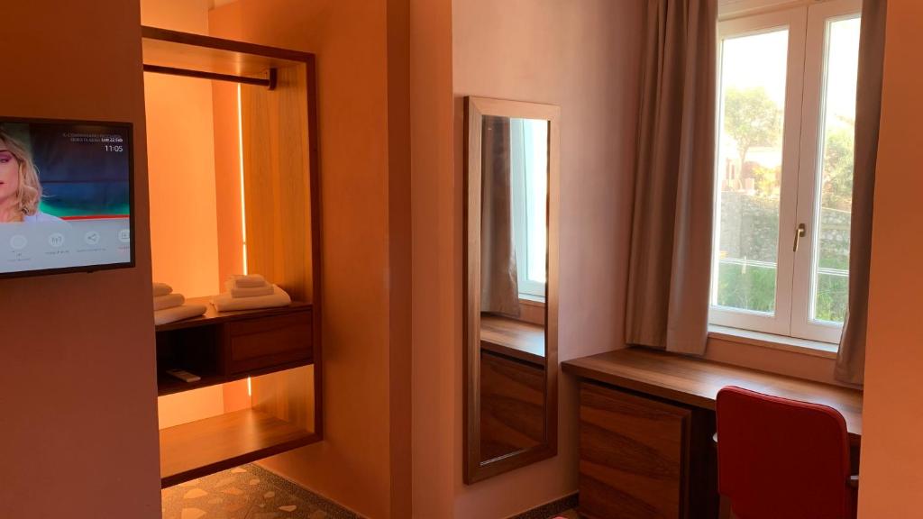 a room with a mirror and a tv and a window at Dimora del Leone Gaeta in Gaeta