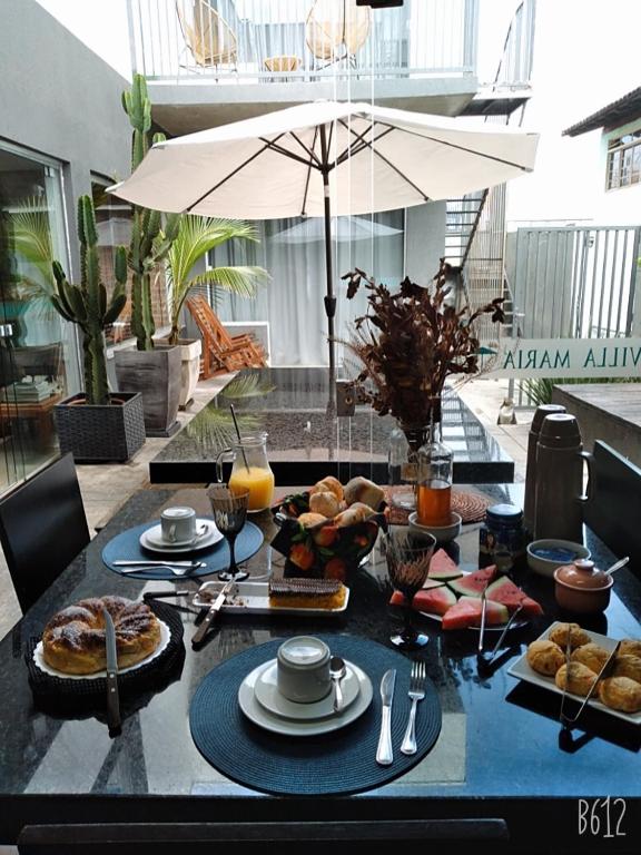 a table with food on it with an umbrella at Villa Maria in Capitólio