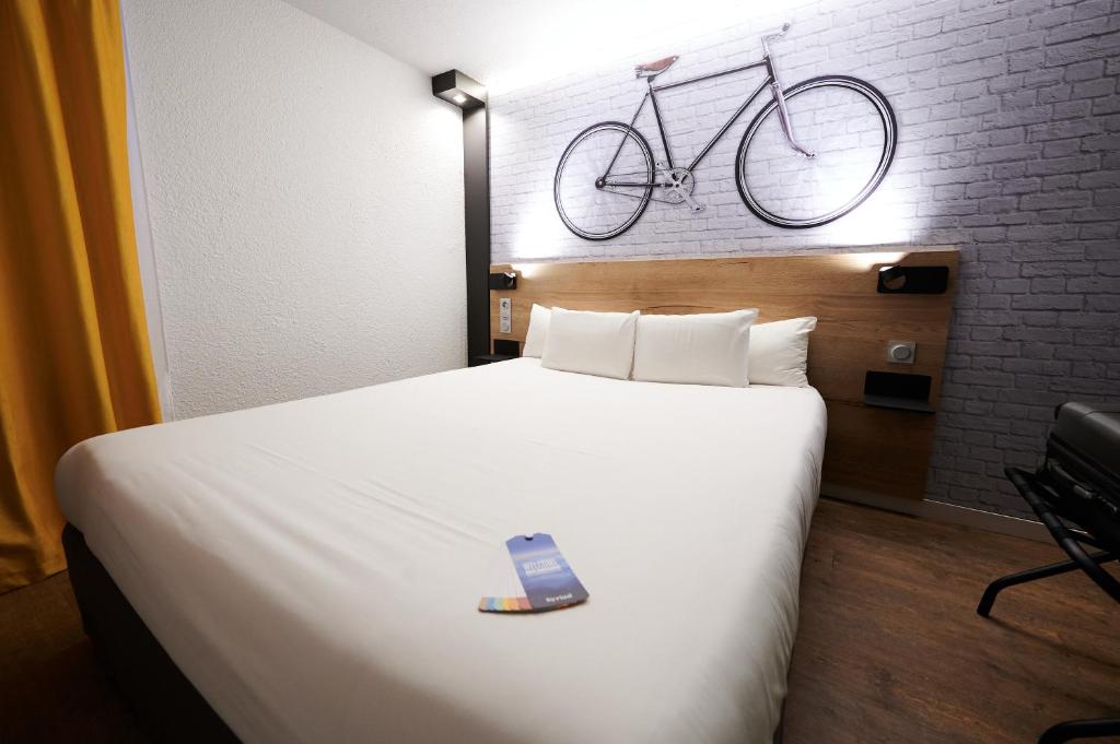 ein Schlafzimmer mit einem Bett mit einem Fahrrad an der Wand in der Unterkunft Kyriad Hotel Laval in Laval