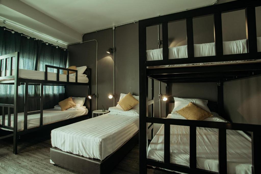 a bedroom with two bunk beds with white sheets at Fashen Poshtel in Chiang Mai