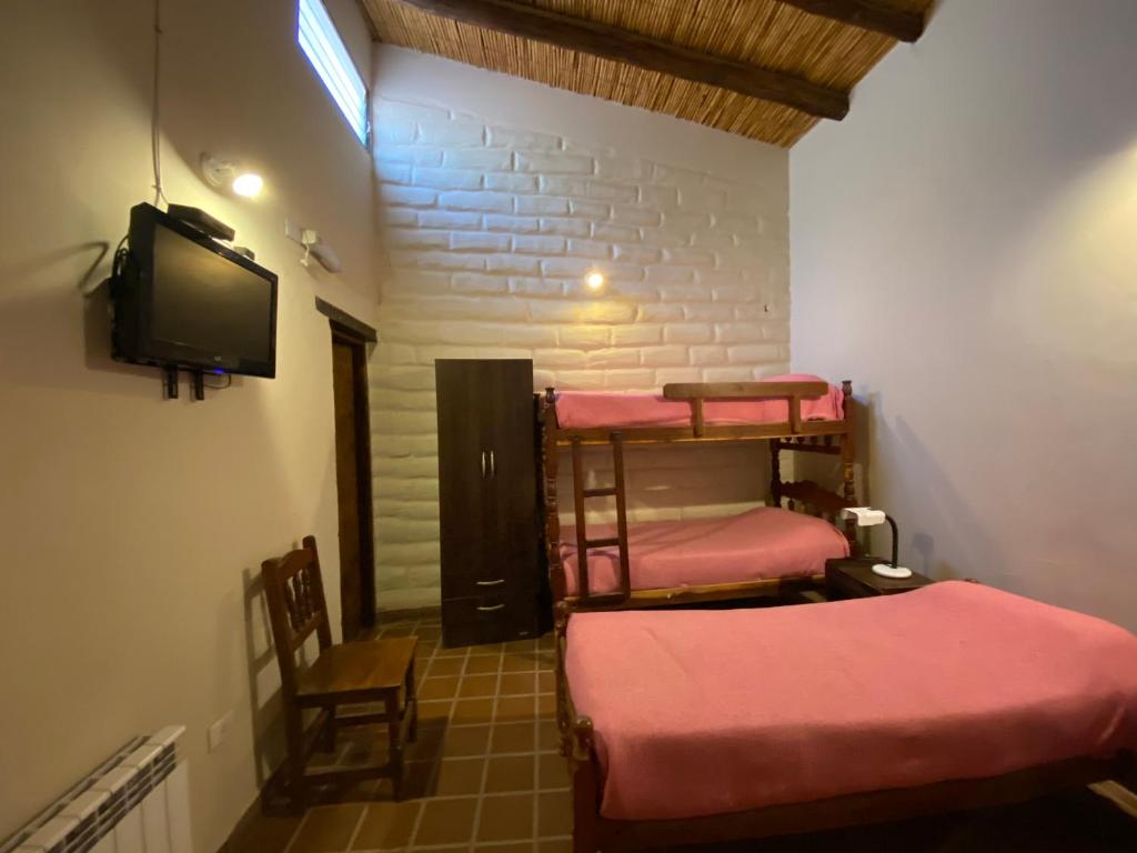 Hosteria Las Tinajas في تيلكارا: غرفة بها أربعة أسرة بطابقين وتلفزيون بشاشة مسطحة