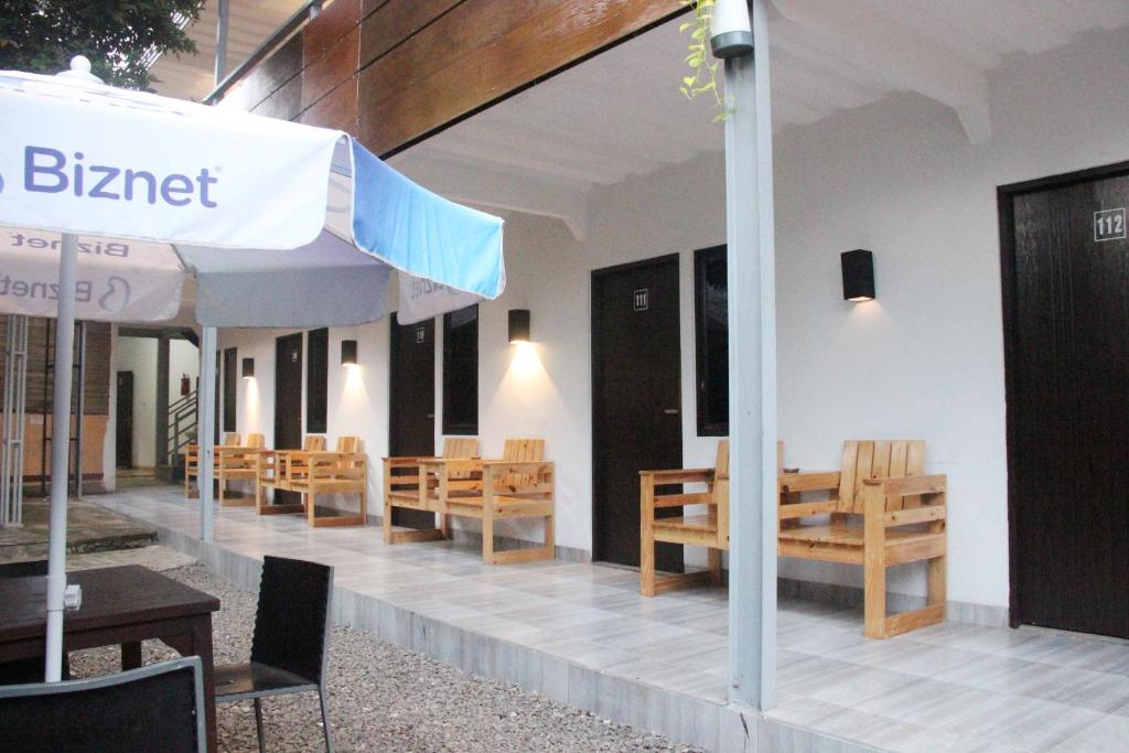 restauracja z drewnianymi krzesłami i parasolem w obiekcie Bamboe Inn Homestay w mieście Bandar Lampung
