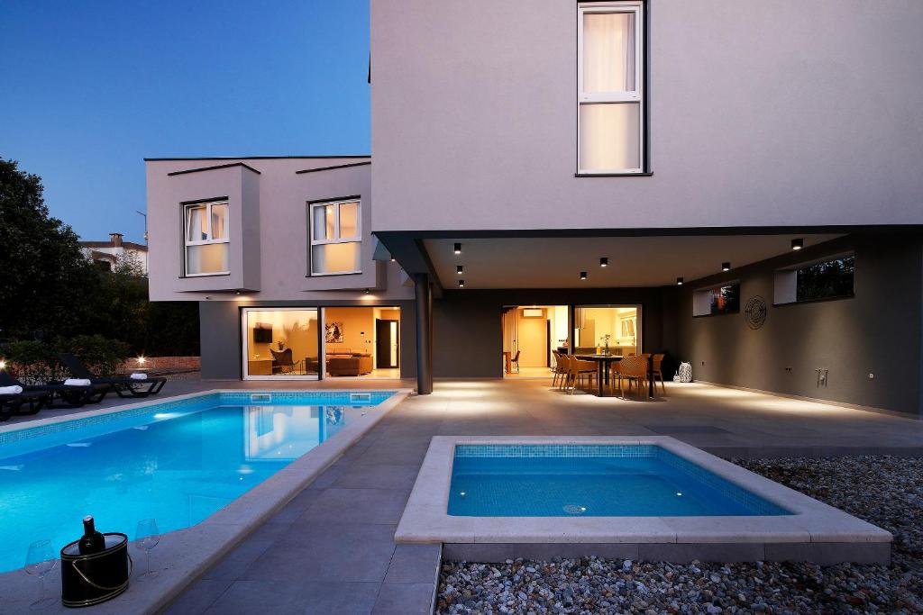 a house with a swimming pool in front of it at VillaLanterna in Malinska